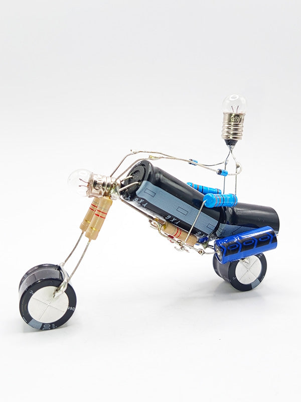 Une figurine en forme de moto de type chopper, fabriquée à partir de composants électroniques tels que des condensateurs, des résistances et des petites ampoules
