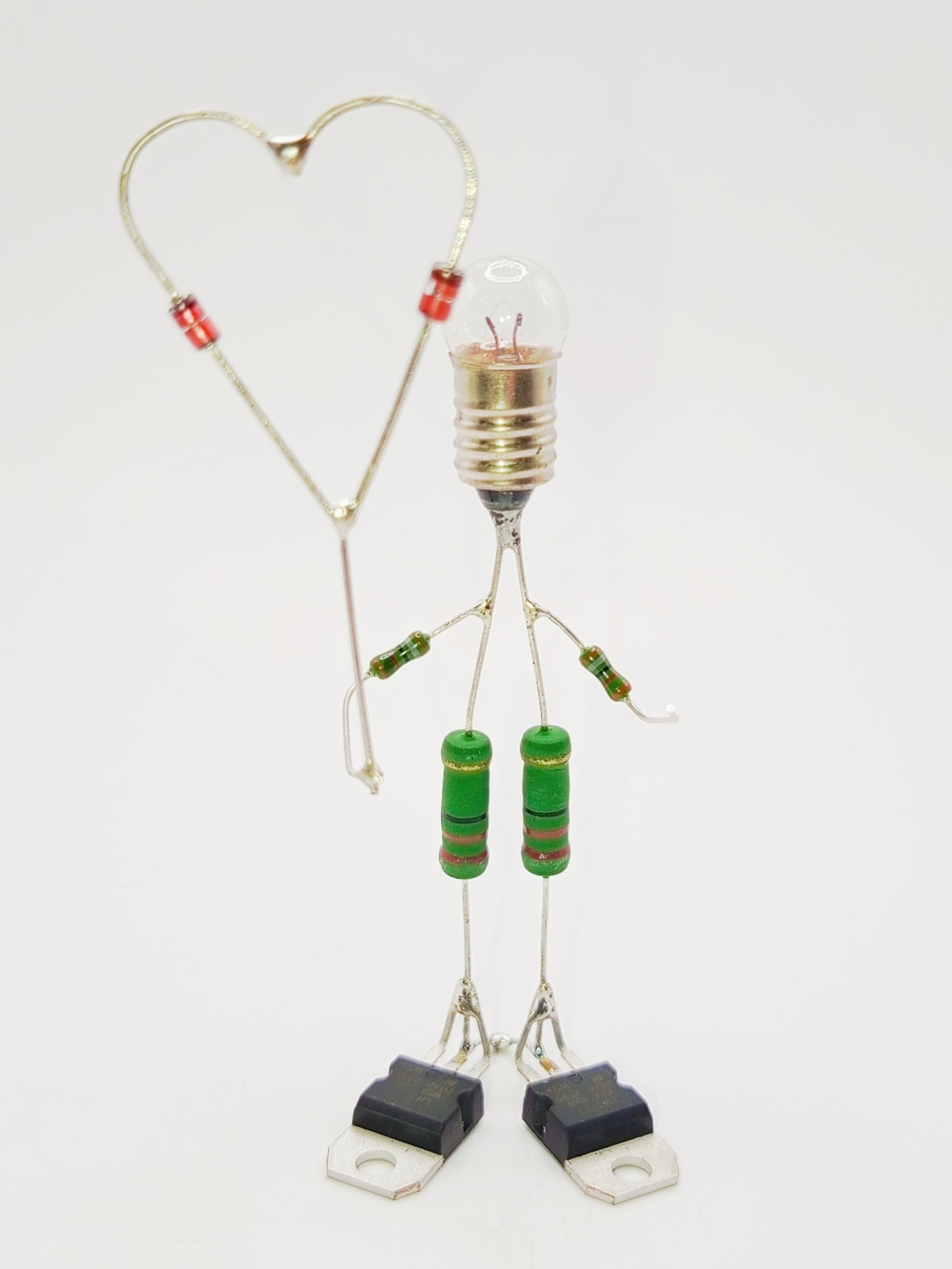 Figurine ou sculpture représentant un personnage qui offre un coeur miniature fabriquée avec des composants électroniques recyclés